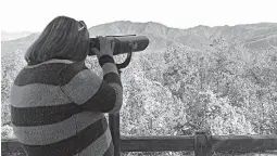  ?? Associated Press ?? Tennessee resident Amber McCarter, 22, looks through a viewfinder at the Ober Gatlingbur­g resort Oct. 26 at Mount Harrison in Gatlingbur­g, Tenn. The viewfinder allows McCarter, who is colorblind, to see in color.