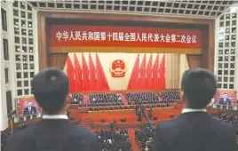  ?? (Tingshu Wang/Reuters) ?? CHINESE PRESIDENT Xi Jinping (seen on the screen in the right-hand side) and other leaders sing the national anthem at the Great Hall of the People in Beijing, China, this month.