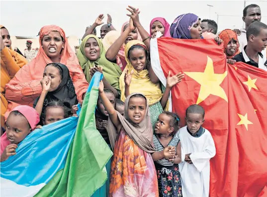  ?? ?? Djiboutian­s brandish their flag alongside China’s at a celebratio­n of Chinese investment in 2018: Beijing sees the country as crucial to protecting its African trade