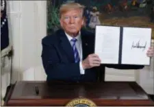  ?? EVAN VUCCI — THE ASSOCIATED PRESS ?? President Donald Trump shows a signed Presidenti­al Memorandum after delivering a statement on the Iran nuclear deal from the Diplomatic Reception Room of the White House, Tuesday in Washington.