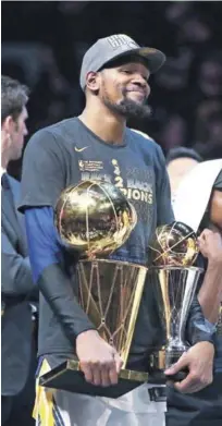  ?? AP ?? Kevin Durant es todo sonrisa y sostiene dos de los trofeos obtenidos por los Warriors en su más reciente corona obtenida.