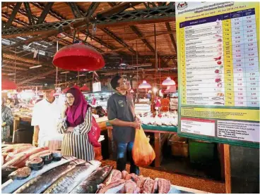  ??  ?? Keeping in check: A shopper looking at a banner list of price-controlled goods at Pasar Taman Keramat in Kuala Lumpur.