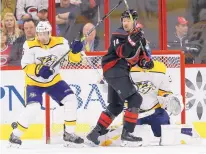  ?? GERRY BROOME/ASSOCIATED PRESS ?? Carolina’s Justin Williams (14) and Nashville’s Dan Hamhuis, left, try to locate the puck during Sunday’s game in Raleigh, N.C. The Hurricanes beat the Predators, 6-3.