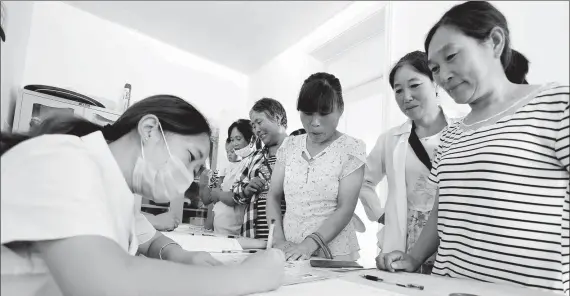  ?? ZHANG KAIHU / FOR CHINA DAILY ?? Women register to accept a free breast and cervical cancer screening at Shiliu community center in Donghai county, Jiangsu province, on July 21, 2017.