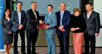  ??  ?? Koh (third left) and Lo (fourth right) formalise the partnershi­p between CTC Malaysia and Cardzone while flanked by executives of both teams.