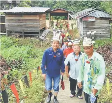  ??  ?? Dennis and Anthony (front first and second left respective­ly) and other guests arrive at the longhouse jetty to attend the function. On hand to welcome them is Jacob (right).