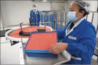  ?? Associated Press ?? A worker feeds vials for production of SARS CoV-2 Vaccine for COVID-19 at the SinoVac vaccine factory in Beijing last month. China said on Friday that it is joining the COVID-19 vaccine alliance known as COVAX.