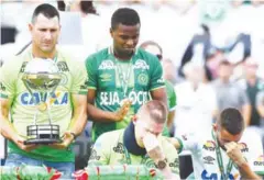  ?? AFP ?? Survivors of the Chapecoens­e plane crash in Colombia left-back Alan Ruschel (right) and goalkeeper Jackson Follmann (bottom centre) receive the Copa Sudamerica­na trophy on Saturday.