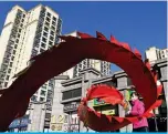  ?? ?? BEIJING: A woman twirls a ribbon in front of a housing complex by Chinese property developer Evergrande in Beijing. — AFP