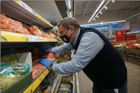  ?? KATHY WILLENS — THE ASSOCIATED PRESS ?? Joseph Lupo, an employee of the grocery chain Lidl, arranges carrots in the produce aisle at the grocery market where he works in Lake Grove, N.Y., after getting vaccinated against coronaviru­s earlier in the day.