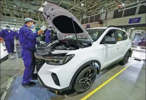  ?? ZHU XINGXIN / CHINA DAILY ?? Employees work on the production line of a carmaker in Shanghai.