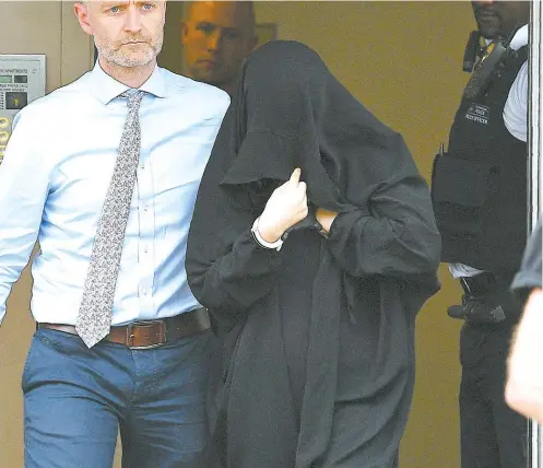  ??  ?? Deux femmes (photo du haut et en bas à gauche) ont été escortées par des policiers lors d’une série de perquisiti­ons menées dans un immeuble de logements à Barking, une banlieue multiethni­que de Londres.