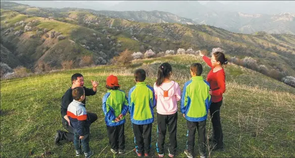  ?? HU HUHU / XINHUA ?? Xu Zhihong (left) and Zhou Xihua, both special education teachers, take students to experience nature on a mountain in Huocheng county, the Xinjiang Uygur autonomous region.