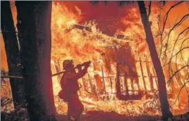  ?? AP ?? A firefighte­r sprays water as flames consume a home in Magalia, California.