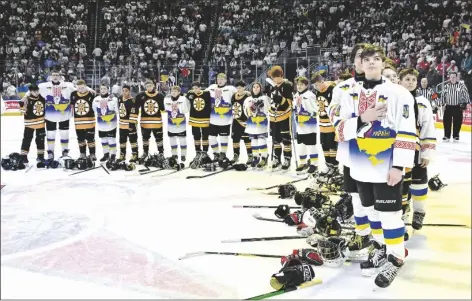  ?? THE CANADIAN PRESS VIA AP ?? UKRAINE AND BOSTON JUNIOR BRUINS PEEWEE TEAMS stand together during the national anthems before a game on Saturday in Quebec City.