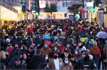  ?? (File Photo/AP/Manu Fernandez) ?? People wearing face masks to protect against the spread of coronaviru­s walk Dec. 8 along a commercial street in downtown Madrid.