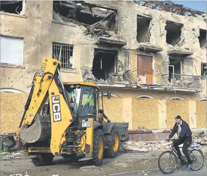 ?? ?? Un hombre en bici pasa junto a un edificio completame­nte destrozado por los brutales impactos de misiles rusos en Zaporiya.