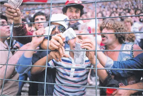  ?? FOTO: IMAGO ?? WM 1982 in Gijón: Algerische Fans wedeln anlässlich des Skandalspi­els zwischen Deutschlan­d und Österreich, das ihr Team aus dem Rennen wirft, mit Geld.