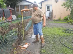  ?? JACQUELINE DORMER/ AP ?? Daniel Noll Sr. measures the flood water level in his backyard in Tremont, Pa. on Tuesday.