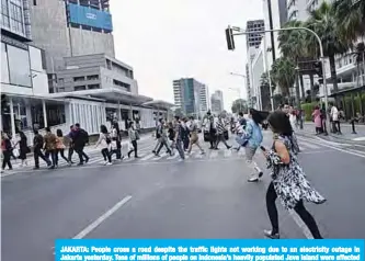  ??  ?? JAKARTA: People cross a road despite the traffic lights not working due to an electricit­y outage in Jakarta yesterday. Tens of millions of people on Indonesia’s heavily populated Java Island were affected by a widespread electricit­y outage on August 4 after disruption­s at several power plants, the state utility PLN said. —AFP