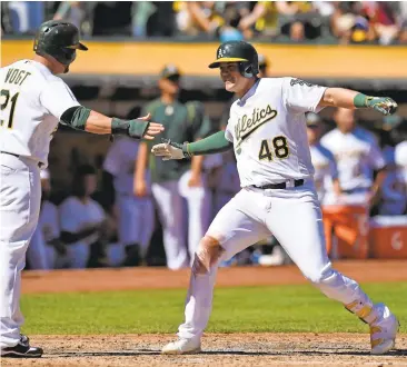  ?? JOSE CARLOS FAJARDO/STAFF ?? A’s infielder Ryon Healy (48) celebrates with teammate Stephen Vogt after homering against the Rangers last September. The third-round pick from Oregon in 2013 has found that swinging less has helped him rebound from a slow start.