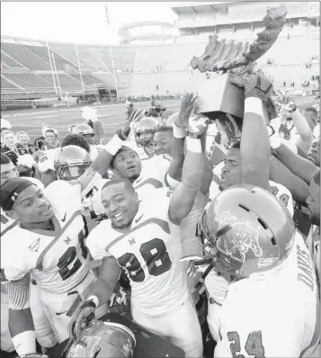  ?? PHOTOS BY HAL YEAGER/ASSOCIATED PRESS ?? Memphis players celebrate with The Bones trophy after defeating UAB 46-9 in their annual “Battle for the Bones” rivalry.