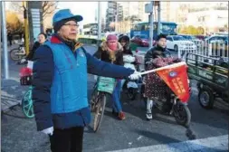  ??  ?? 12 月 19日，海淀黄庄地铁站附近，志愿者老梁正在维持交­通秩序。他今年4月加入山猫纵­队，是第一次参加志愿者活­动。