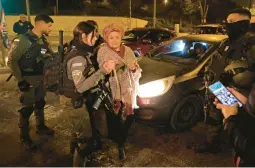  ?? AHMAD GHARABLI/GETTY-AFP ?? Israeli security forces escort a woman who was blocking vehicles during a protest Saturday night at the Shuafat refugee camp in east Jerusalem.