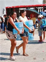  ?? ?? ■ Damnificad­os por el huracán “Otis” cargan paquetes con agua embotellad­a que les servirá para cocinar y beber.
