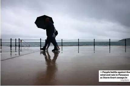  ?? Greg Martin ?? > People battle against the wind and rain in Penzance as Storm Evert sweeps in
