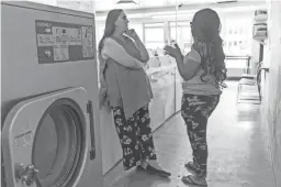  ??  ?? Christy Moore, owner of Social Spin Laundromat, talks to Hanan Dema, 21, at a laundromat in Phoenix. Moore employs aged-out foster teens like Dema.