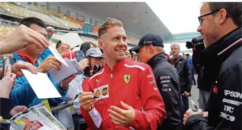  ?? FOTO: WONG/AP/DPA ?? Die Frisur ist ein wenig eigenwilli­g, die Unterschri­ft begehrt wie immer: Ferrari-Pilot Sebastian Vettel hofft auf den Hattrick zum Saisonstar­t.