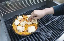  ?? PHOTOS BY TRAVIS HEYING/WICHITA EAGLE ?? When making peach cobbler on the grill, you cook the peaches until bubbly, then add the dough.