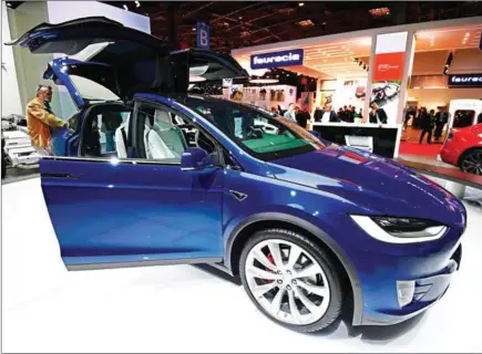  ?? MIGUEL MEDINA/AFP ?? A man inspects a Tesla model X during the Paris Motor Show on September 30, 2016. Tesla Motors overtook General Motors to become the biggest US automaker by market capitalisa­tion Monday, a sign of how Silicon Valley has captured investor excitement at...