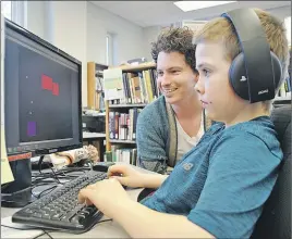  ?? CAROL DUNN/THE NEWS ?? Alex MacNeil watches Bryan Ross play the video game he created during sessions this week at the Stellarton Library. MacNeil has been teaching a group of young people how to code, and other sessions are coming up this month at several other area libraries.