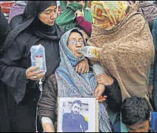  ?? PTI ?? The mother of missing Noida university student holds his picture during a protest in Srinagar on Thursday.