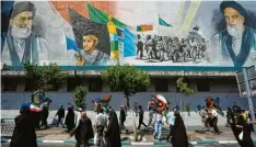  ?? Foto: Vahid Salemi, AP, dpa ?? Iranische Gläubige gehen an einem Wandgemäld­e vorbei, das den verstorben­en Revolution­sführer Ayatollah Khomeini zeigt.