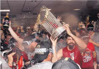  ?? DAVID J. PHILLIP/ASSOCIATED PRESS ?? Washington third baseman Anthony Rendon, hoisting the World Series trophy, celebrates in the locker room with his Nationals teammates after winning the title Wednesday night in Houston.