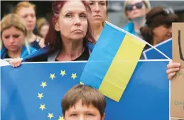  ?? OLIVIER MATTHYS/AP ?? Supporters of Ukraine’s inclusion in the European Union show their approval Thursday outside the EU summit in Brussels. The bloc approved the action unanimousl­y.