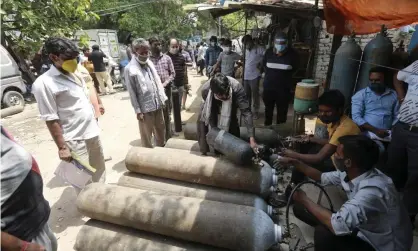  ??  ?? ‘Without oxygen it’s impossible to treat a severely ill Covid patient, but there’s a global shortage.’ People queue to refill oxygen cylinders in New Delhi, India, 23 April. Photograph: AP