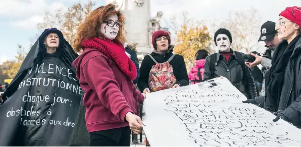  ??  ?? Activistas con un cartel que contiene los nombres de mujeres víctimas de la violencia doméstica se manifestar­on ayer en París.