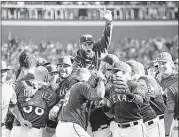  ?? JIM COWSERT / TRIBUNE NEWS SERVICE ?? Rangers starting pitcher Nick Martinez (top) joins the celebratio­n after Texas defeated the Los Angeles Angels 9-2 to clinch the AL West title on the final day of the regular season.