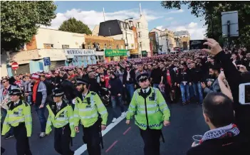  ??  ?? Am frühen Abend machen sich die Fans des 1. FC Köln in einem gemeinsame­n Marsch aus der Londoner Innenstadt auf in Richtung Emirates-Stadion. Eskortiert werden sie von der Polizei.
