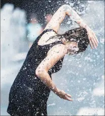  ?? AP PHOTO ?? A woman cools down in a water fountain as she beats the heat in Montreal.