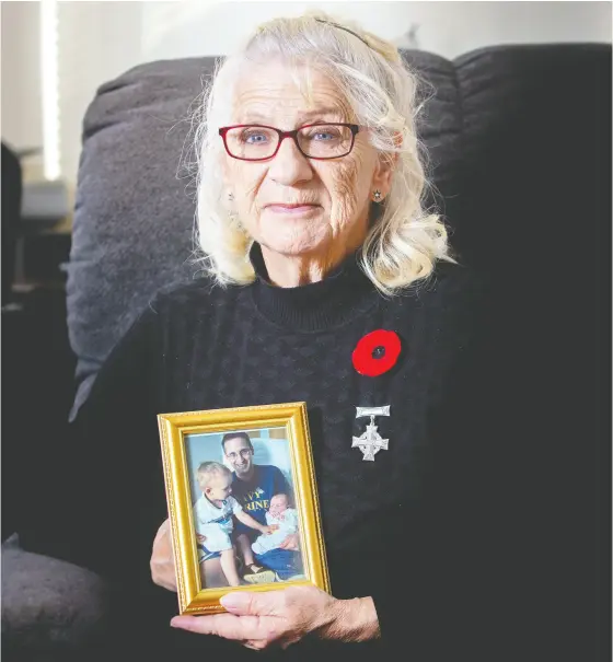  ?? James West / The Cana dian Press ?? Debbie Sullivan holds a photo of her son Christophe­r Saunders and his two sons while wearing her National Silver Cross at her home
in Summervill­e, N.B., on Saturday. Saunders, a naval officer, lost his life in 2004 while serving aboard HMCS Chicoutimi.