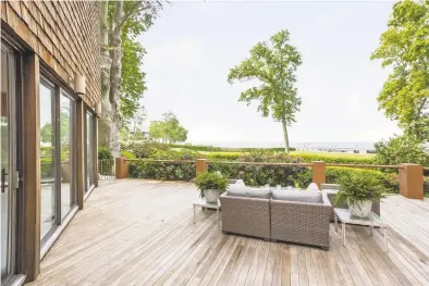  ?? Houlihan Lawrence Darien / ?? The large, inviting deck of this Darien home overlooks Long Island Sound, making it the ideal spot for outdoor activity. Below, a stylish pergola caps off a patio, filtering the sun.