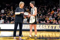  ?? MATTHEW PUTNEY/THE ASSOCIATED PRESS ?? Iowa coach Lisa Bluder presents Caitlin Clark with a commemorat­ive ball after Thursday’s game against Michigan in Iowa City, Iowa. Clark broke the NCAA women’s career scoring record.