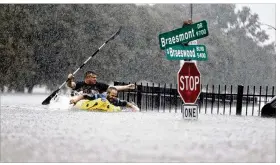  ?? MARK MULLIGAN / HOUSTON CHRONICLE ?? Two kayakers try to beat the current pushing them down an overflowin­g bayou in Houston on Sunday. Rescuers answered hundreds of calls as floodwater­s from the remnants of Hurricane Harvey climbed high enough to begin filling second-story homes.