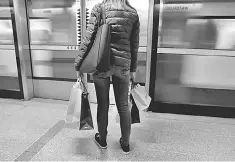  ??  ?? A woman carries her shopping bags before boarding a train on the London Undergroun­d at Waterloo Station in London. Britain’s financial services industry paid a record 72.1 billion pounds (US$96.2 billion) in tax during the past fiscal year, PwC said in...