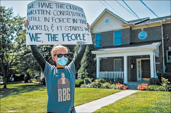  ?? BRANDON BELL/GETTY ?? A woman holds up a sign Saturday at the Louisville, Kentucky, home of Senate Majority Leader Mitch McConnell.